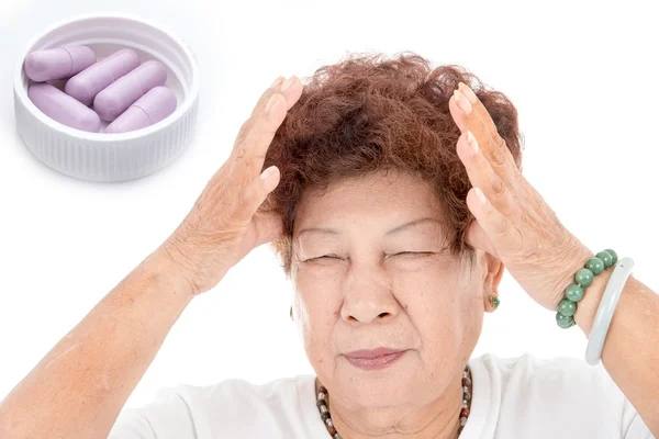 Asian Senior Thai woman having headace and purple capsules on wh — Stock Photo, Image