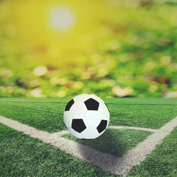 Bal op voetbalveld en oranje bokeh en zon flare — Stockfoto