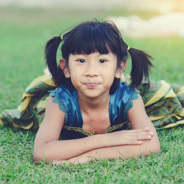 Азиатка в платье принцессы лежит на траве и смотрит на камеру — стоковое фото