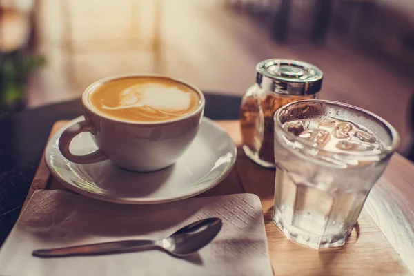 Tasse à café avec sucre brun et verre d'eau posé sur un boa en bois — Photo
