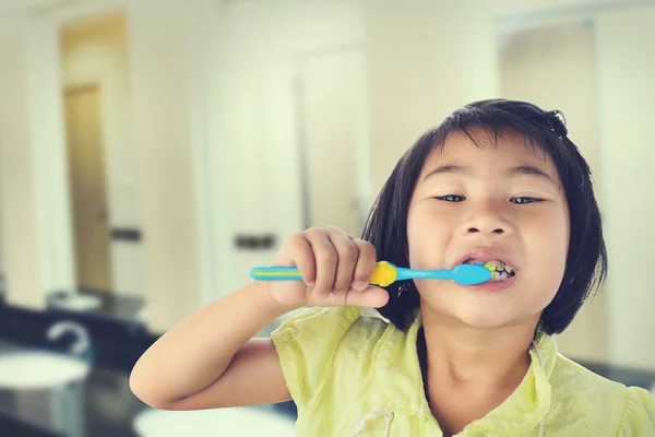 Petite fille se brossant les dents isolées sur fond de toilette — Photo