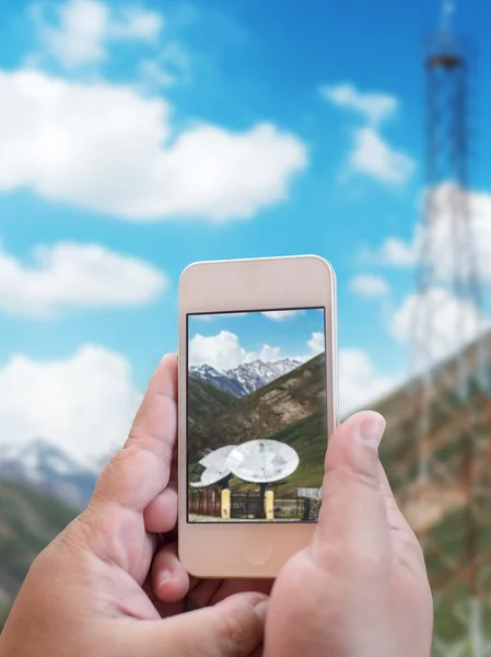 Mano celebración de teléfono móvil con antena grandes antenas parabólicas y s —  Fotos de Stock