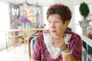 Cafe 'de çay içen mutlu Asyalı son sınıf öğrencisi kadın.
