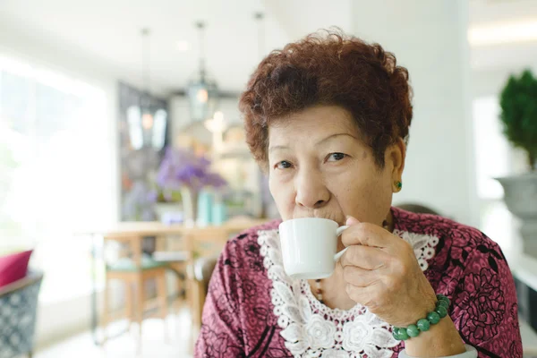 Szczęśliwy Azji starszy kobieta picia herbaty w kawiarnia. — Zdjęcie stockowe
