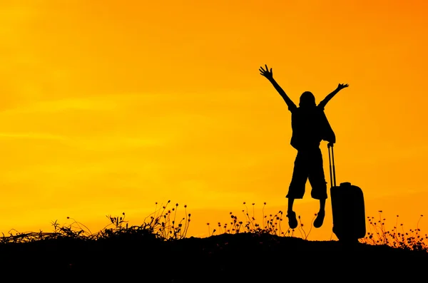 stock image Jumping boy with a suitcase on a meadow at sunset 