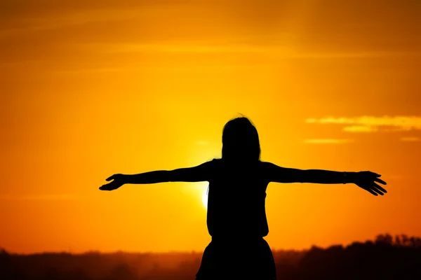 Young woman with raised hands standing on land over sunrise — Stock Photo, Image