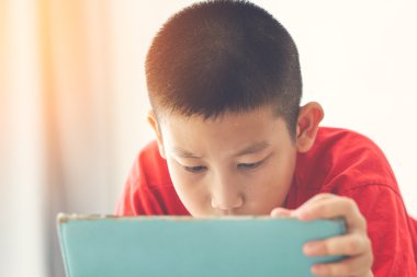 Asyalı çocuk kardeşler yatak ve tablet kullanma.