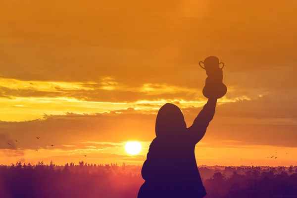 Braços levantando o troféu vencedor com nascer do sol — Fotografia de Stock