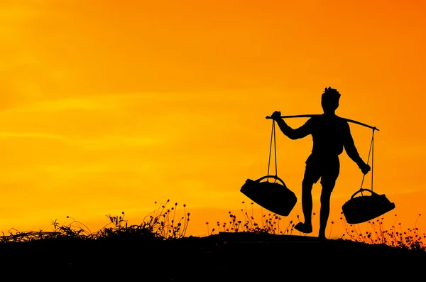 Silhouette di Worker trasportare cesto di sale a campo salato, Thailandia — Foto Stock