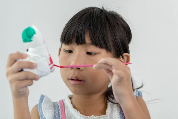 Asian child paints the colors of white plaster doll toys on the — Stock Photo, Image