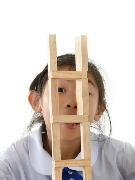 Asian girl in uniform looking through wooden block on white back — Stock Photo, Image