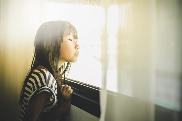 Asiática chica mirando por la ventana —  Fotos de Stock