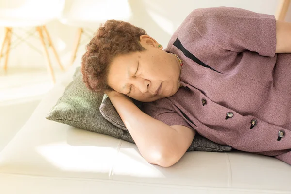 Asian senior Woman Resting on Couch with Pillow at the Living Ro — Stock Photo, Image