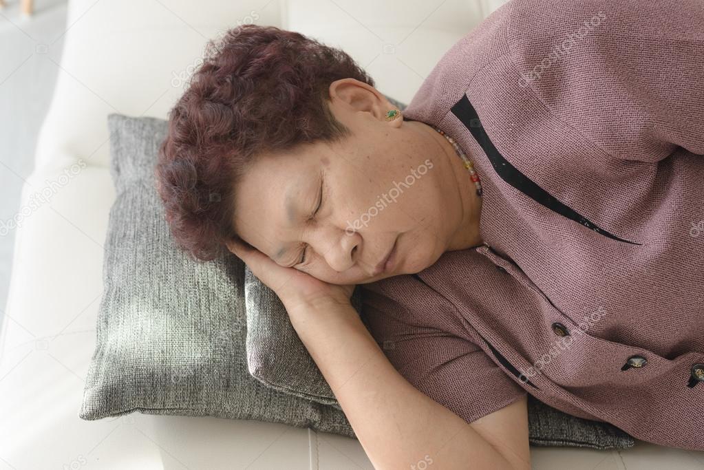 Asian senior Woman Resting on Couch with Pillow at the Living Ro