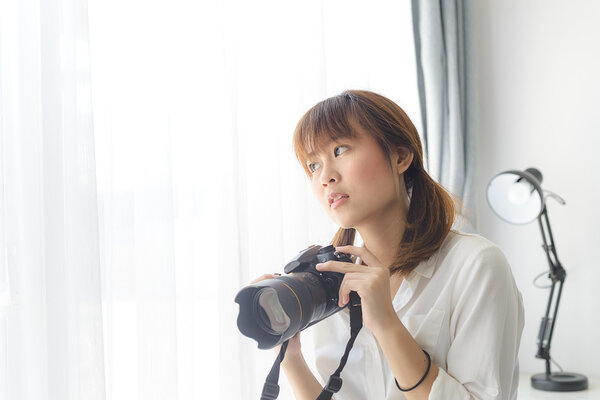 Asian Teenage girl with digital camera at home