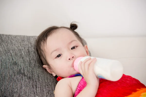 Bébé en pleurs avec une bouteille de lait à la maison . — Photo