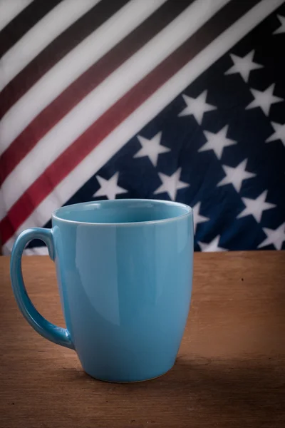 Tasse à café bleue sur table en bois avec fond drapeau des États-Unis . — Photo