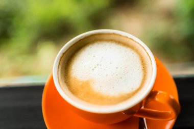 Turuncu kahve fincanı doğa bokeh arka plan ile.