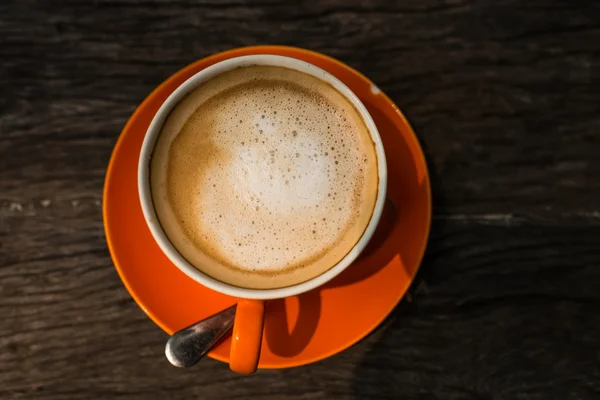 Ahşap doku arka plan ile turuncu kupa kahve latte. — Stok fotoğraf