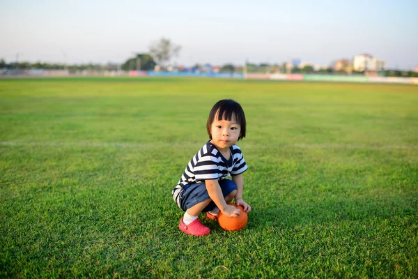 Asian girl playing ball in green field. — Stock Photo, Image