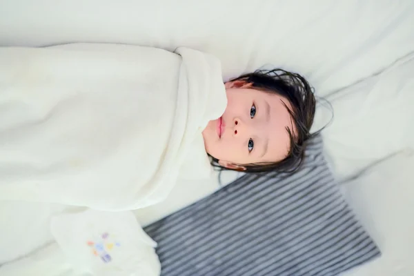 Aziatische meisje in witte handdoek liggend op bed. — Stockfoto