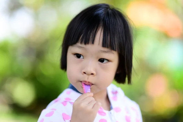 公園でアイスクリームを食べるかわいいアジアの女の子. — ストック写真