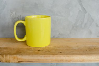 Kirli sarı kahve fincanı gri arka plan karşı ahşap raf.