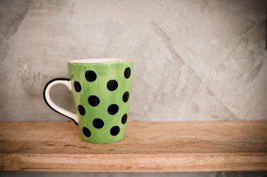 Ahşap arka plan ve çimento duvar üzerinde noktalı yeşil Kupası.