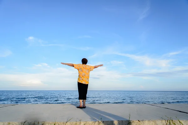 Back of Senior Woman With Arms Outstretched at Pranburi beach. T — Stock Photo, Image