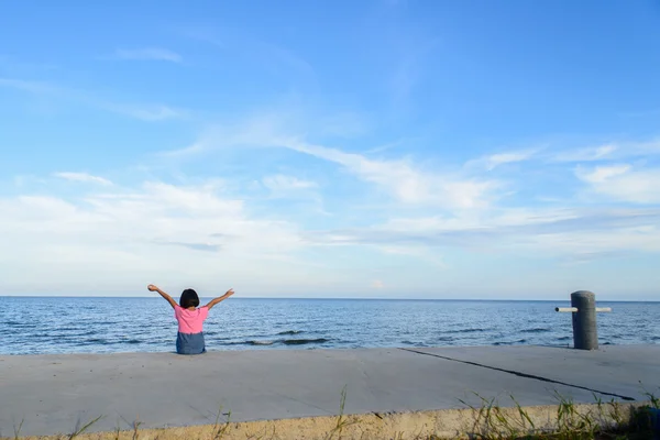 Seduta ragazza alzare le mani con cielo blu e spiaggia, la libertà — Foto Stock