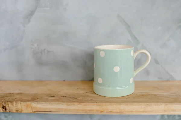 Tazza verde pastello con puntino su fondo in legno e parete in cemento . — Foto Stock