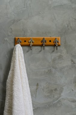 Beyaz beton duvar maruz Bathr içinde bol dökümlü havlu asılı