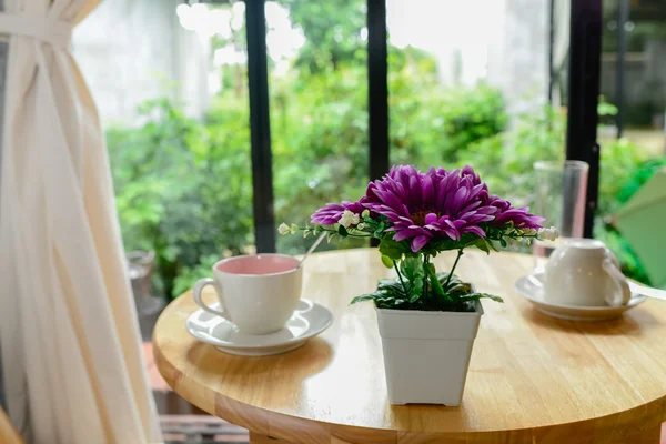 Caneca de café e vaso de flores na mesa de madeira . — Fotografia de Stock