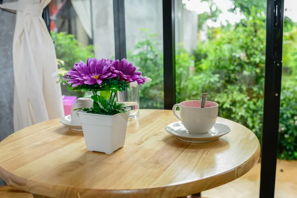 Caneca de café e vaso de flores na mesa de madeira . — Fotografia de Stock