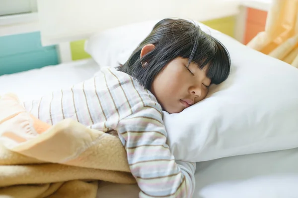 Aziatisch meisje slapen op bed bedekt met deken. — Stockfoto