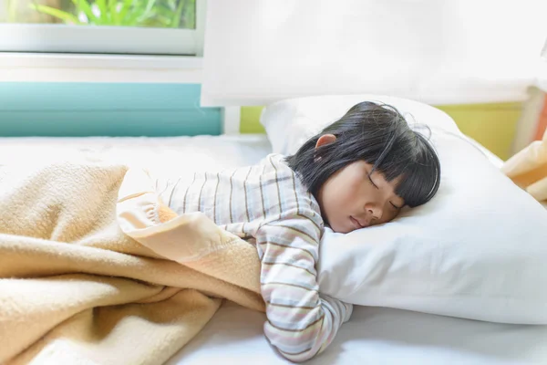 Aziatisch meisje slapen op bed bedekt met deken. — Stockfoto