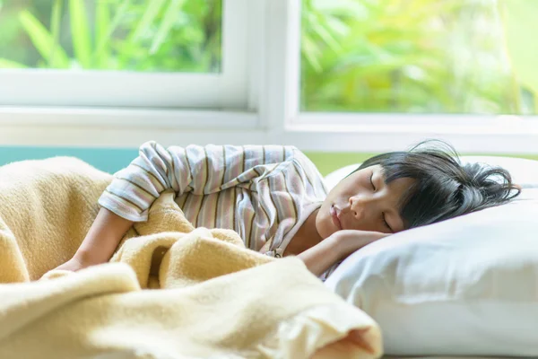 Asian girl sleeping on bed covered with blanket. — Stock Photo, Image