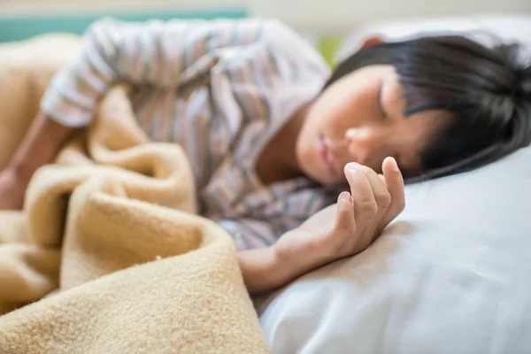 Aziatische meisje slapen op bed bedekt met een deken. Selectieve aandacht — Stockfoto