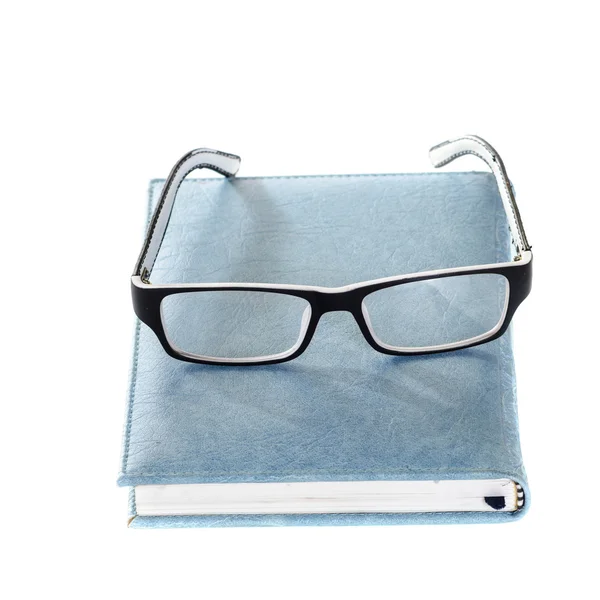 Close notebook and glasses isolated on white. — Stock Photo, Image