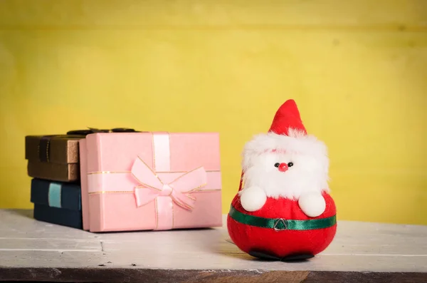Vintage ef ile sarı arka plana sahip Santa oyuncak ve hediye kutuları — Stok fotoğraf
