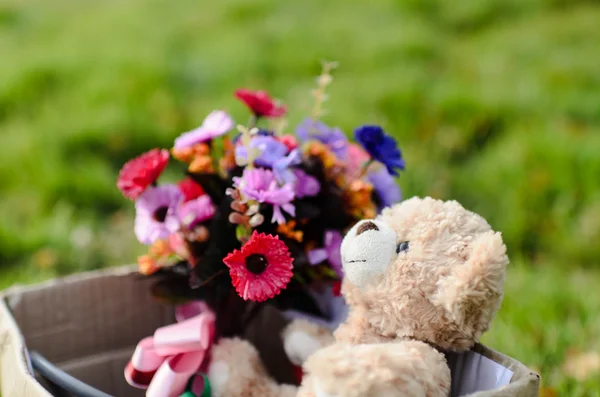 Orso e mazzo di fiori in scatola marrone su erba verde con naturale — Foto Stock
