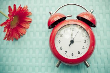 Retro çalar saat ve gerbera çiçek mavi doku arka plan üzerinde.