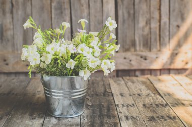 Vintage tarzı ahşap arka plan üzerinde beyaz çiçekler paslanmaz pot, 