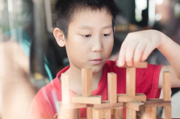 Asian boy playing with the wood game (jenga). — Stock Photo, Image