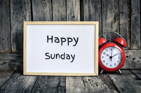 Happy Sunday messae på hvidt bord og rød retro ur ved woode - Stock-foto