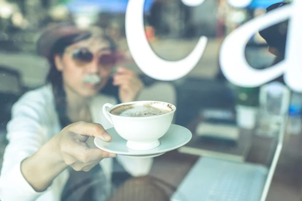 Mujer asiática bebiendo café y usando la computadora en la cafetería . — Foto de Stock