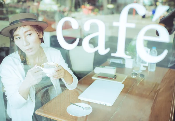 Asiatisk kvinna dricka kaffe och använder dator i café. — Stockfoto