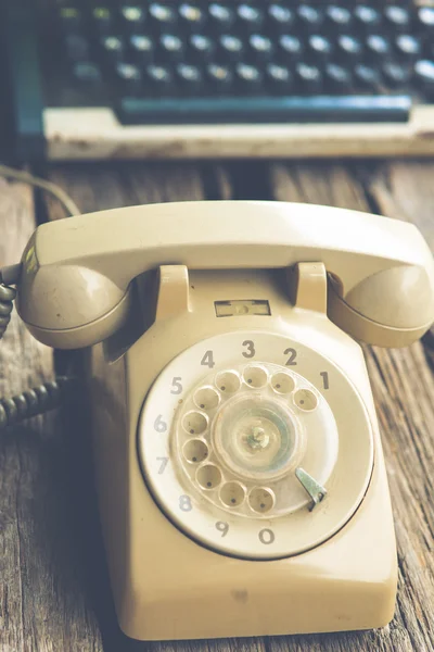 Teléfono retro giratorio y máquina de escribir sobre fondo de madera . — Foto de Stock