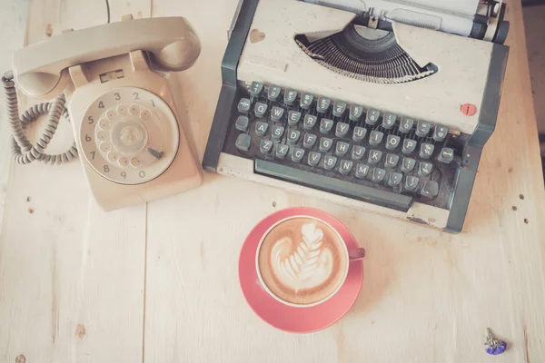Taza de café con leche roja con teléfono vintage y máquina de escribir en wo —  Fotos de Stock