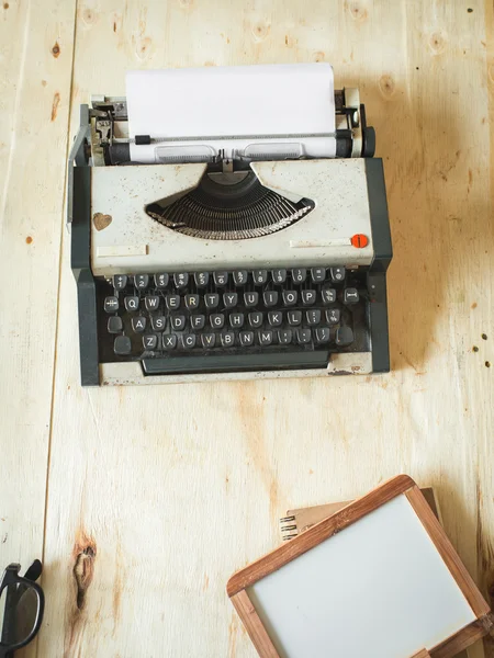 Máquina de escribir y pizarra blanca sobre fondo de madera . — Foto de Stock